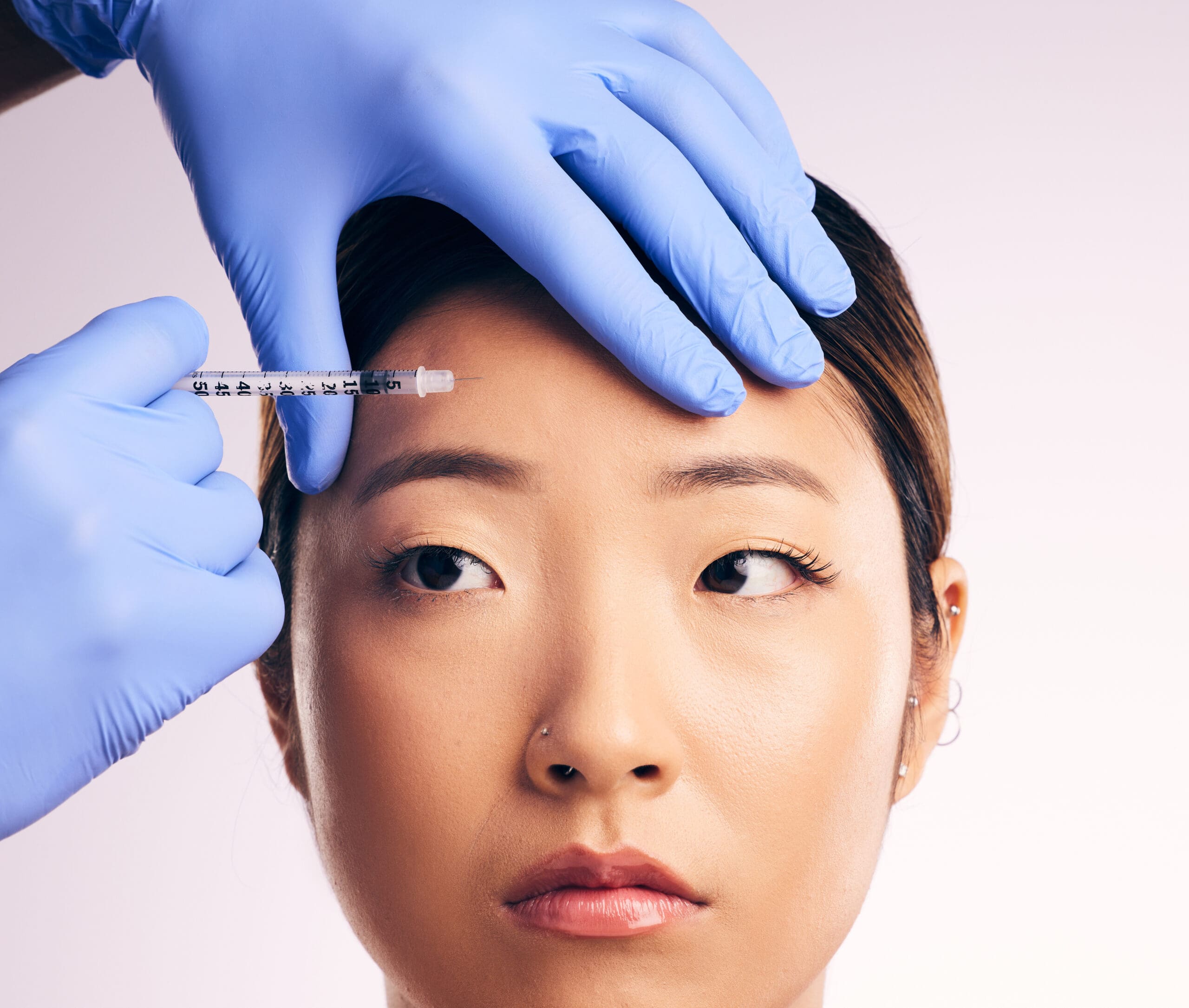 Professional-Injector-performing-treatment-on-asian-womans-forehead | Passion Beauty Academy Professional botox Injector performing treatment on asian woman's forehead